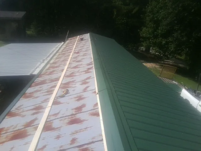 Old rusted panels beside newly installed green metal roofing — Wind Damage Roof Repair by Roofing Brothers in Castaic