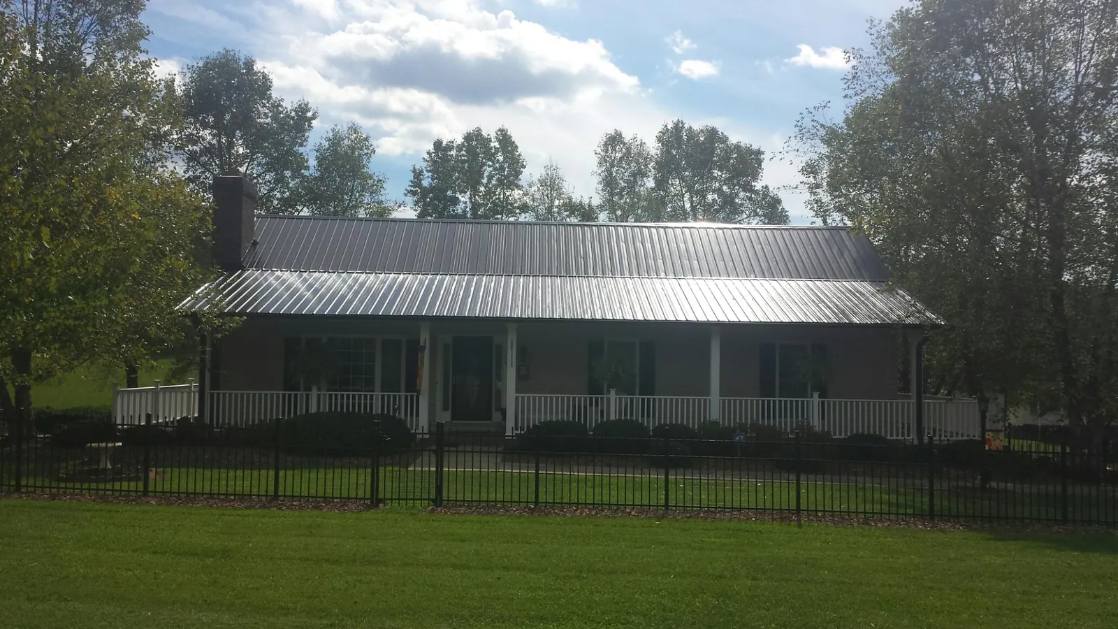 Gray metal roof on a brick ranch with a full width front porch — Gutter Guard Installation work by our crew in Castaic
