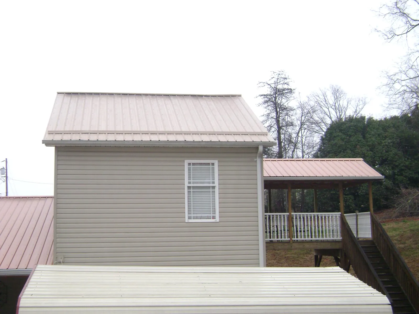 Tan metal roofs on a two story addition and attached porch, from a Roof Replacement job in Castaic