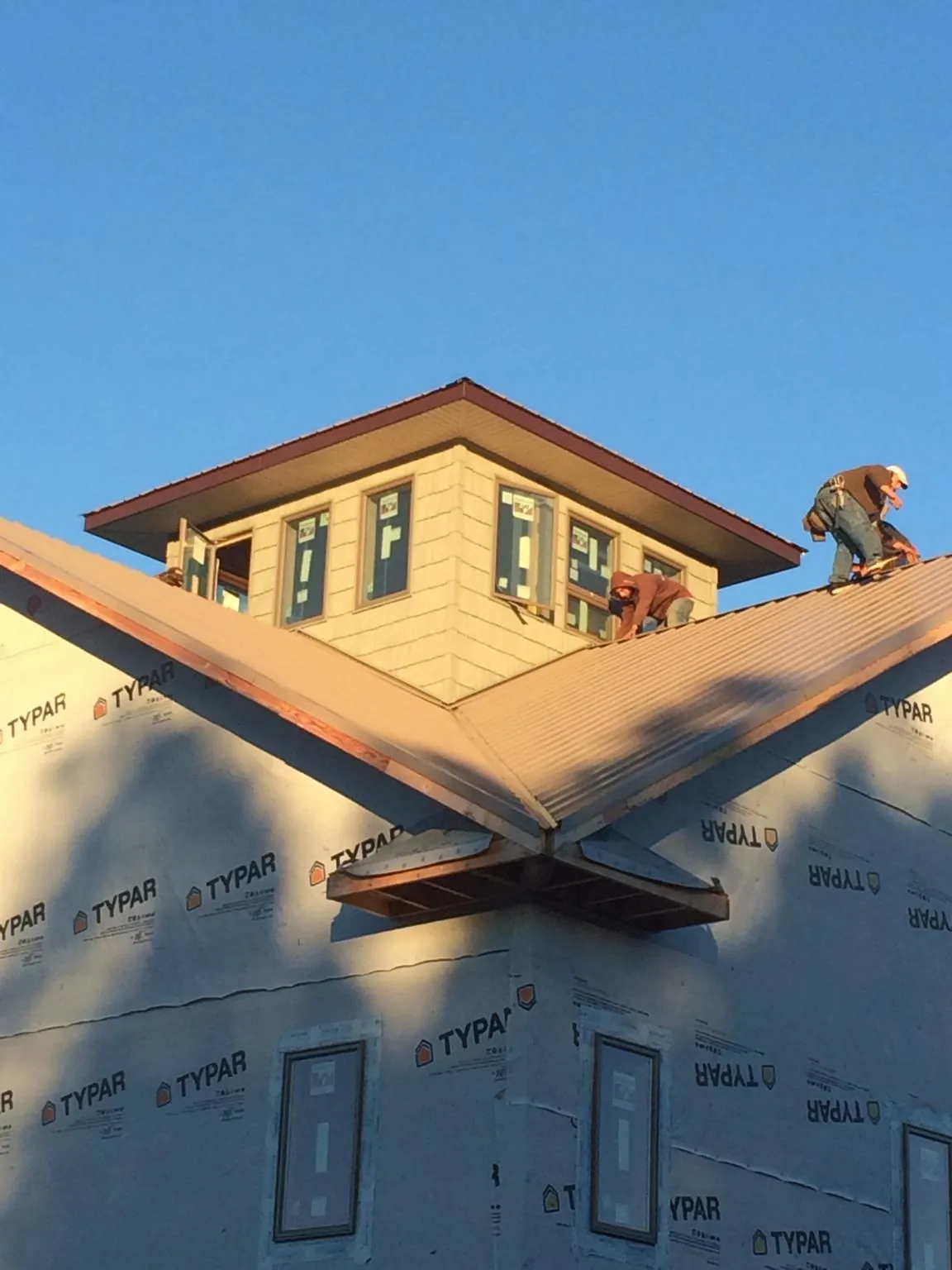 Roofers working around a rooftop cupola on a new metal roof at sunset — Roof Waterproofing in Castaic by Roofing Brothers
